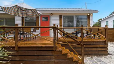 a house with a wooden deck with an umbrella at Coastal Charm in Santa Rosa Beach