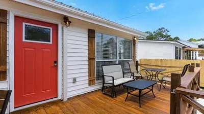 a red door on a house with chairs and a table at Coastal Charm in Santa Rosa Beach