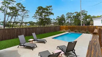 a patio with chairs and a swimming pool at Coastal Charm in Santa Rosa Beach