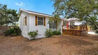 a small white house with a porch and a deck at Coastal Charm in Santa Rosa Beach