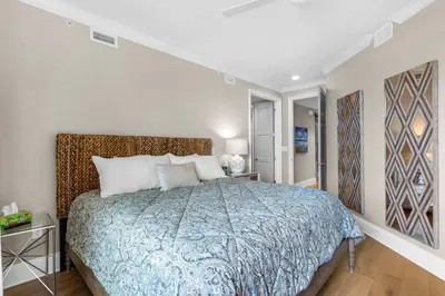 a bedroom with a bed with a blue comforter at Casa Del Oro Penthouse at Barrett Square - Downtown Rosemary Beach Pool &Hot Tub Access in Rosemary Beach