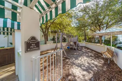 a backyard with a fence and a playground at Casa Del Oro Penthouse at Barrett Square - Downtown Rosemary Beach Pool &Hot Tub Access in Rosemary Beach