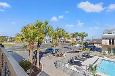 a resort with a pool and palm trees and a parking lot at Ocean Breeze 5D in Panama City Beach