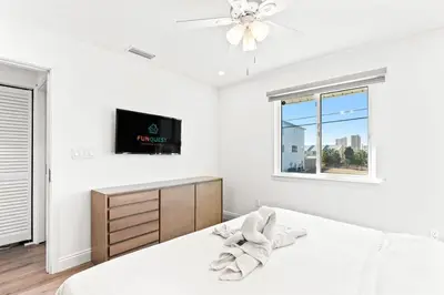 a white bedroom with a bed and a tv at Ocean Breeze 5C in Panama City Beach