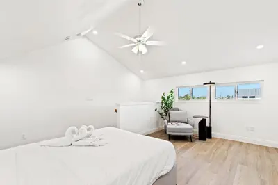 a white bedroom with a bed and a ceiling fan at Ocean Breeze 5C in Panama City Beach