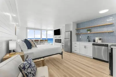 a bedroom with a bed and a kitchen with the ocean at Beach Front Ocean View Condo - Top of the Gulf 521 in Panama City Beach