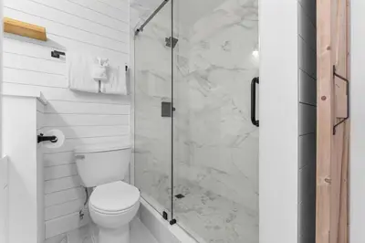 a bathroom with a toilet and a glass shower at Beach Front Ocean View Condo - Top of the Gulf 521 in Panama City Beach