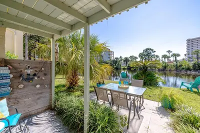 a patio with a table and chairs next to a river at Captain's Quarters at Gulf Highlands Beach Resort in Panama City Beach