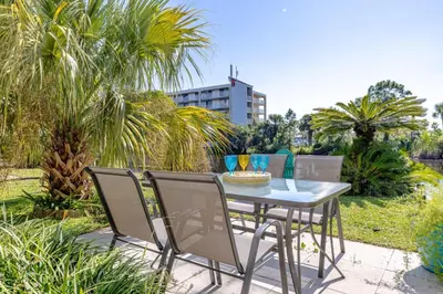 a table and chairs sitting on a patio with palm trees at Captain's Quarters at Gulf Highlands Beach Resort in Panama City Beach