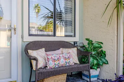 a wicker chair sitting on a porch with pillows at Captain's Quarters at Gulf Highlands Beach Resort in Panama City Beach