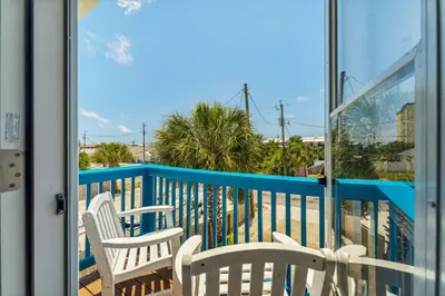 a balcony with two white chairs and a glass door at Beach Walkers by Beach Haven Vacation Rentals in Panama City Beach