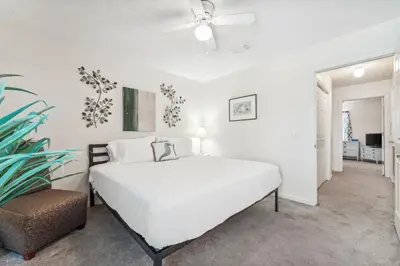 a white bedroom with a bed and a chair at Beach Walkers by Beach Haven Vacation Rentals in Panama City Beach