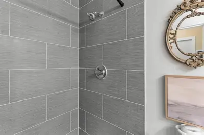 a bathroom with a gray tiled shower with a mirror at Top of the Gulf 507 Beach Front Resort Ocean View in Panama City Beach