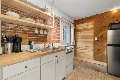 a kitchen with white cabinets and a brick wall at Cowboy Cottage by Beach Haven Vacation Rentals in Panama City Beach