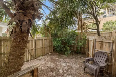 a chair sitting under a palm tree next to a fence at Cowboy Cottage by Beach Haven Vacation Rentals in Panama City Beach