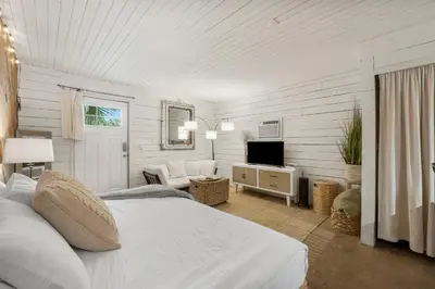 a white bedroom with a bed and a television at Cowboy Cottage by Beach Haven Vacation Rentals in Panama City Beach
