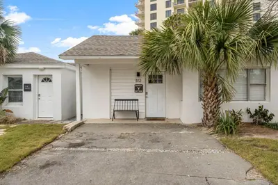 a palm tree in front of a white house at Cowboy Cottage by Beach Haven Vacation Rentals in Panama City Beach