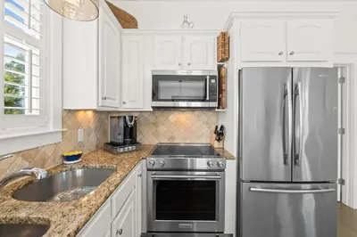 a kitchen with white cabinets and a stainless steel refrigerator at 30A Sunset Beach House - Villa Infinity by Panhandle Getaways in Seacrest