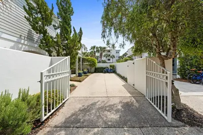 a driveway with a white fence and trees at 30A Sunset Beach House - Villa Infinity by Panhandle Getaways in Seacrest
