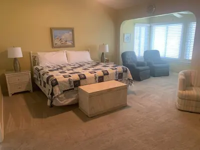 a bedroom with a bed and two blue chairs at Dream Come True in PCB in Panama City Beach