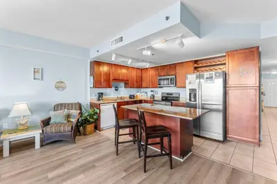 a kitchen with wooden cabinets and a island with bar stools at Laketown Wharf #0613 in Panama City Beach