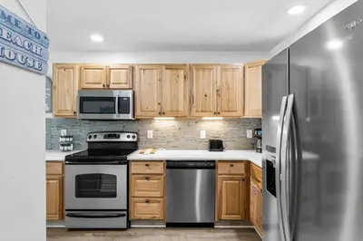 a kitchen with wooden cabinets and a stainless steel refrigerator at Portside Resort AA1 by InJoy Vacations in Panama City Beach