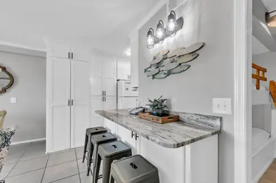 a kitchen with white cabinets and a counter with stools at The Summit 312 in Panama City Beach