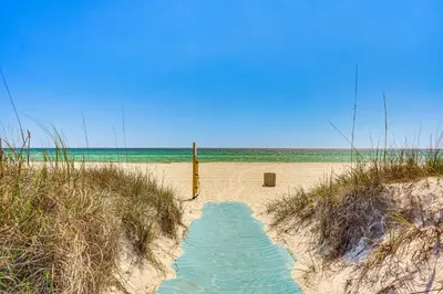 a sandy beach with a path leading to the ocean at Steps to Sand Panama City Beach Apartment! in Panama City Beach