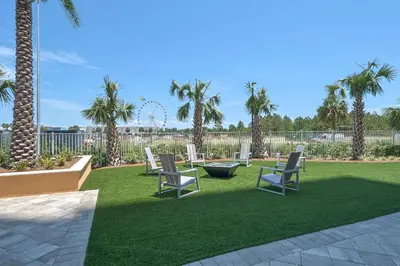 a lawn with chairs and palm trees in a yard at Calypso 3-2007 by Emerald Coast Retreats in Panama City Beach