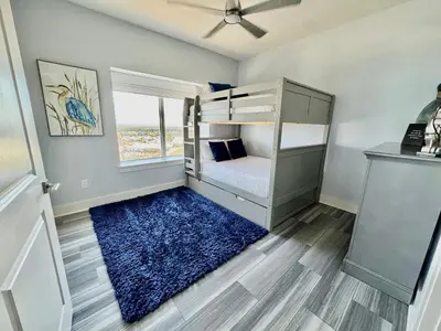a bedroom with a bunk bed and a blue rug at Calypso 3-2112 by Emerald Coast Retreats in Panama City Beach