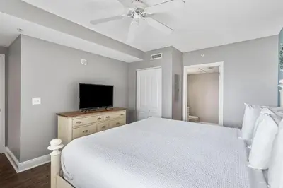 a bedroom with a white bed and a flat screen tv at Emerald Beach Resort 1133 - Beachfront with Breathtaking Views by Beach Haven Vacation Rentals in Panama City Beach