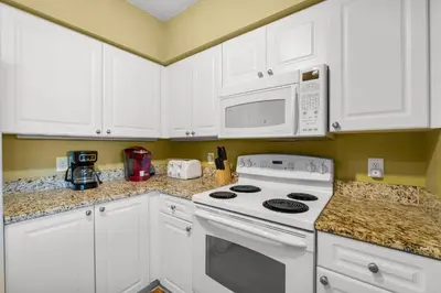 a kitchen with white cabinets and a stove and microwave at Emerald Beach Resort 1834 - Beachfront with Stunning Views by Beach Haven Vacation Rentals in Panama City Beach