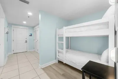 a bedroom with two bunk beds and a table at Grand Panama 1005 - Tower Two - 2 bedroom - Large Deck with Gulf Views by Beach Haven Vacation Rentals in Panama City Beach