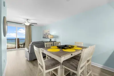 a dining room and living room with a table and chairs at Grand Panama 1005 - Tower Two - 2 bedroom - Large Deck with Gulf Views by Beach Haven Vacation Rentals in Panama City Beach