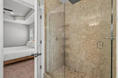 a glass shower in a bedroom with a bed at Nothin But Time by Beach Haven Vacation Rentals in Panama City Beach