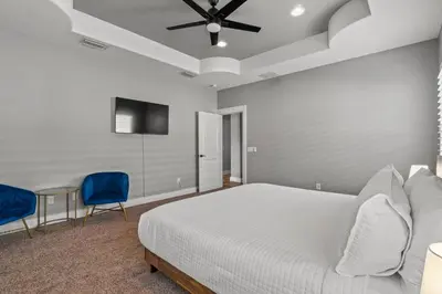 a bedroom with a bed and two blue chairs at Nothin But Time by Beach Haven Vacation Rentals in Panama City Beach