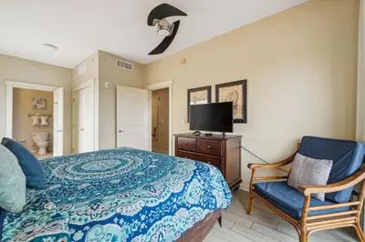 a bedroom with a bed and a tv and a chair at Origin 0427 - One Bedroom - Partial Gulf View by Beach Haven Vacation Rentals in Panama City Beach