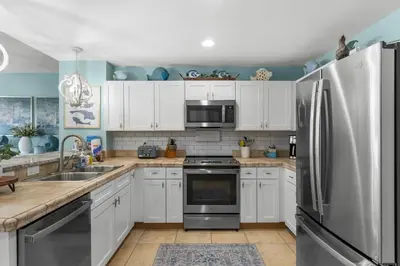 a kitchen with white cabinets and a stainless steel refrigerator at Origin 0507- One Bedroom - Sunset and Gulf Views! by Beach Haven Vacation Rentals in Panama City Beach