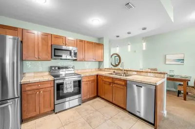 a kitchen with wooden cabinets and stainless steel appliances at Origin 0517 - One Bedroom - Partial Gulf View by Beach Haven Vacation Rentals in Panama City Beach