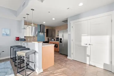 a kitchen with white cabinets and bar stools at Origin 0524 - One Bedroom - Beautiful Gulf Views! by Beach Haven Vacation Rentals in Panama City Beach
