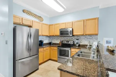 a kitchen with stainless steel appliances and wooden cabinets at The Village Blue Haven Condo - Private Beach Access Pool & Hot Tub in Rosemary Beach