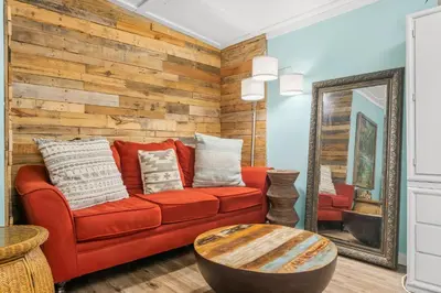 a living room with a red couch and a mirror at Zen Studio by Beach Haven Vacation Rentals in Panama City Beach