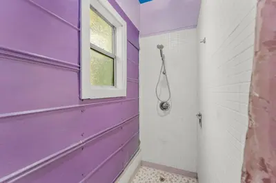 a purple bathroom with a window and a shower at Zen Studio by Beach Haven Vacation Rentals in Panama City Beach