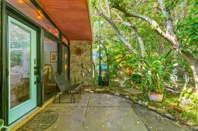 a porch with a glass door and chairs and trees at Zen Studio by Beach Haven Vacation Rentals in Panama City Beach