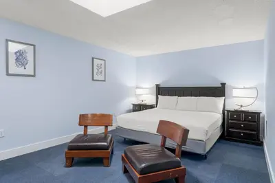 a bedroom with a bed and two chairs and two lamps at Tiki Time 702 by Beach Haven Vacation Rentals in Panama City Beach