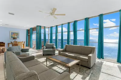 a living room with a couch and chairs and windows at Tiki Time 702 by Beach Haven Vacation Rentals in Panama City Beach