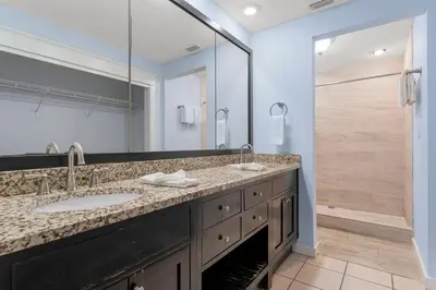 a bathroom with two sinks and a large mirror at Tiki Time 702 by Beach Haven Vacation Rentals in Panama City Beach
