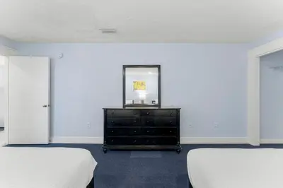 a bedroom with two beds and a dresser with a mirror at Tiki Time 702 by Beach Haven Vacation Rentals in Panama City Beach