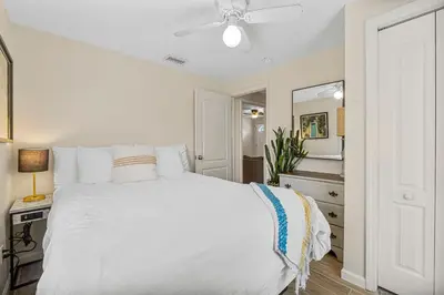 a bedroom with a white bed with a ceiling fan at The Yard by Beach Haven Vacation Rentals in Panama City Beach