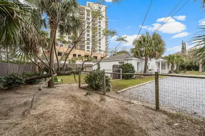 a fence in front of a house with palm trees at The Yard by Beach Haven Vacation Rentals in Panama City Beach